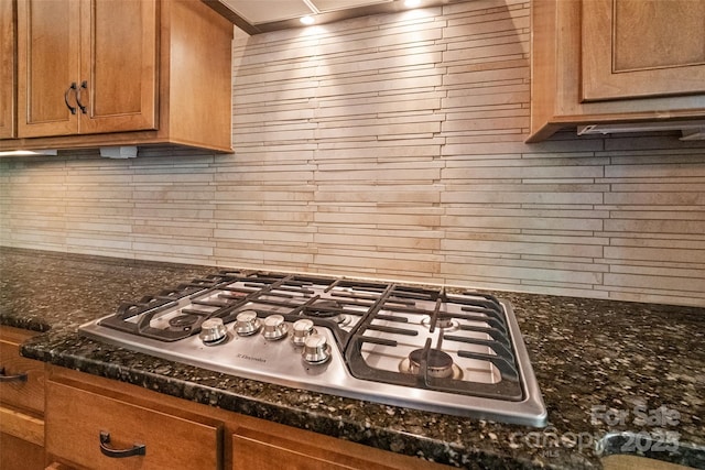 115 Boyce Rd, Charlotte, NC 28211 - kitchen with stainless steel gas stovetop, backsplash, brown cabinetry, and dark stone counters