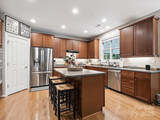 13930 Daltrey Ln, Charlotte, NC 28277 - kitchen with appliances with stainless steel finishes, dark countertops, light wood-style floors, a center island, and recessed lighting