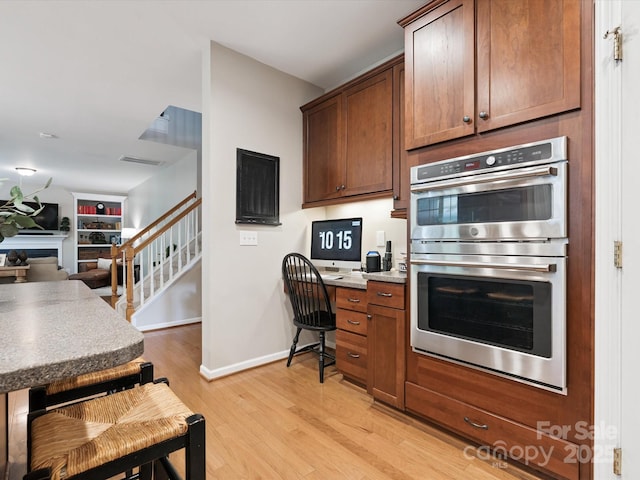 13930 Daltrey Ln, Charlotte, NC 28277 - kitchen with double oven, light wood-style flooring, an office area, open floor plan, and a fireplace