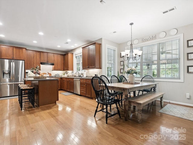 13930 Daltrey Ln, Charlotte, NC 28277 - kitchen with appliances with stainless steel finishes, a chandelier, light wood-style flooring, under cabinet range hood, and recessed lighting