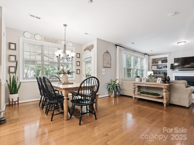 13930 Daltrey Ln, Charlotte, NC 28277 - dining space with light wood-type flooring, a chandelier, and built in shelves