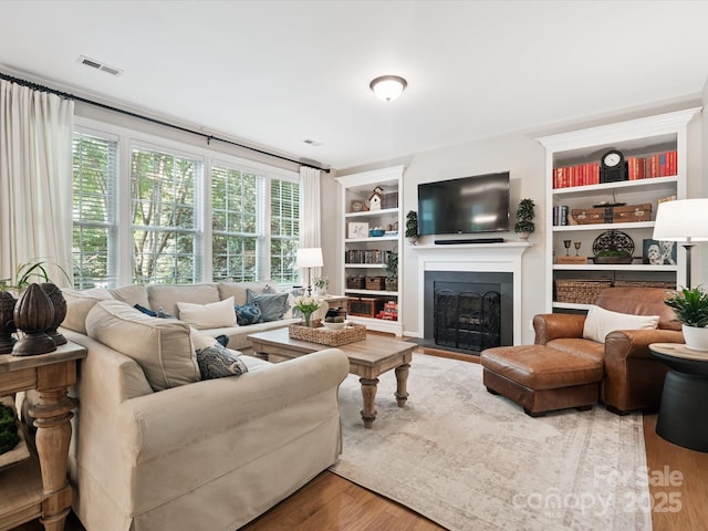 13930 Daltrey Ln, Charlotte, NC 28277 - living area featuring built in features, wood finished floors, and a fireplace with flush hearth