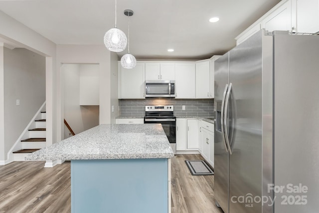 611 King Arthur Dr, Gastonia, NC 28056 - kitchen featuring stainless steel appliances, light wood-style flooring, tasteful backsplash, a center island, and light stone counters