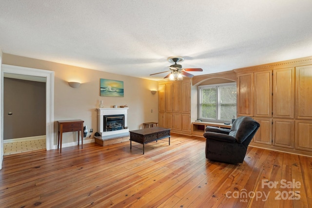 3809 Union Hill Rd, East Bend, NC 27018 - living area featuring light wood-style flooring, a glass covered fireplace, ceiling fan, and a textured ceiling