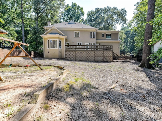 6546 Chestnut Grove Ln, Charlotte, NC 28210 - rear view of house with a wooden deck, a playground, a chimney, stucco siding, and view of wooded area