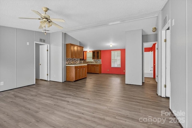 2611 Dallas Stanley Hwy, Stanley, NC 28164 - kitchen with brown cabinets, a ceiling fan, tasteful backsplash, a textured ceiling, and wood finished floors