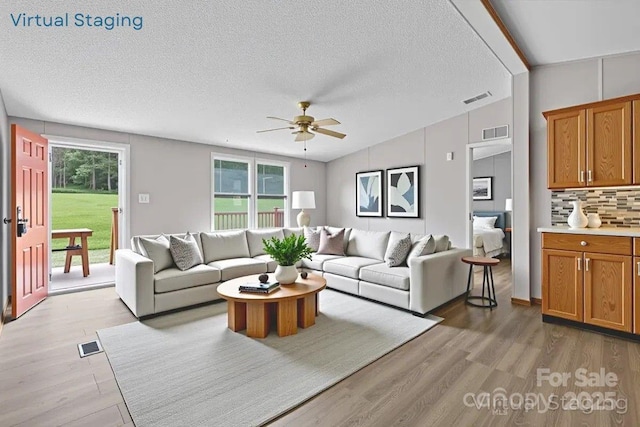 2611 Dallas Stanley Hwy, Stanley, NC 28164 - living area with a ceiling fan, light wood-style floors, lofted ceiling, and a textured ceiling