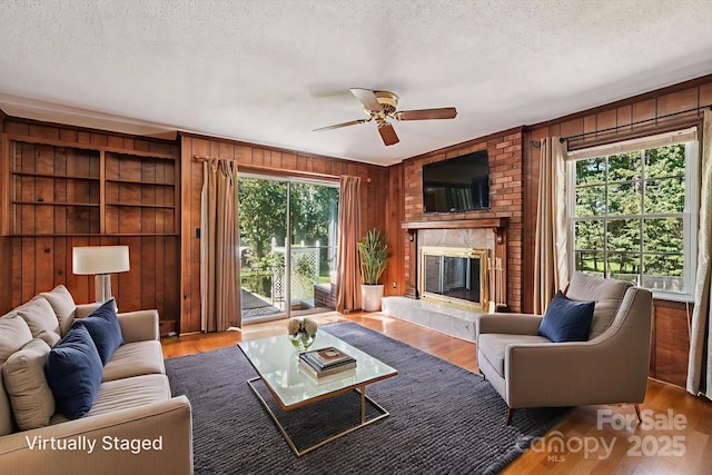 3333 Tanglewood Dr, Rock Hill, SC 29732 - living room with wooden walls, a fireplace, a textured ceiling, a ceiling fan, and wood finished floors