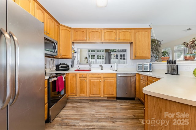 5128 Balsam Bark Ln, Fort Mill, SC 29708 - kitchen with appliances with stainless steel finishes, wood finished floors, light countertops, and a peninsula