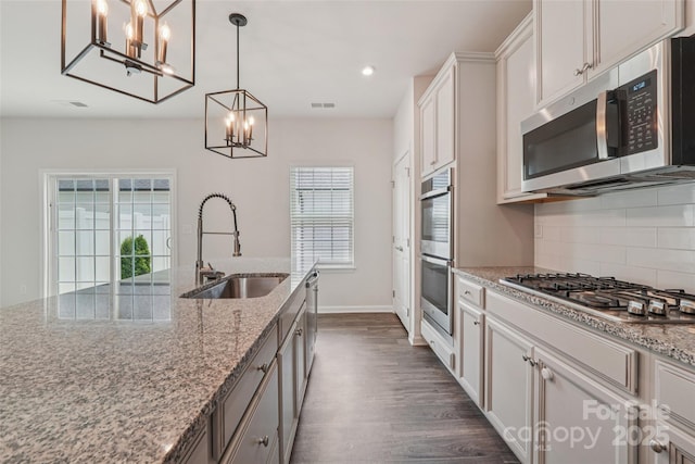 5037 Patton Dr, Gastonia, NC 28056 - kitchen with appliances with stainless steel finishes, a chandelier, decorative backsplash, dark wood finished floors, and light stone counters