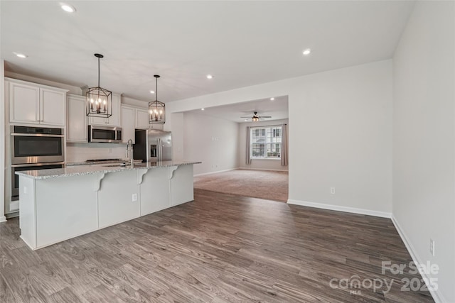 5037 Patton Dr, Gastonia, NC 28056 - kitchen with stainless steel appliances, a center island with sink, wood finished floors, a breakfast bar, and recessed lighting