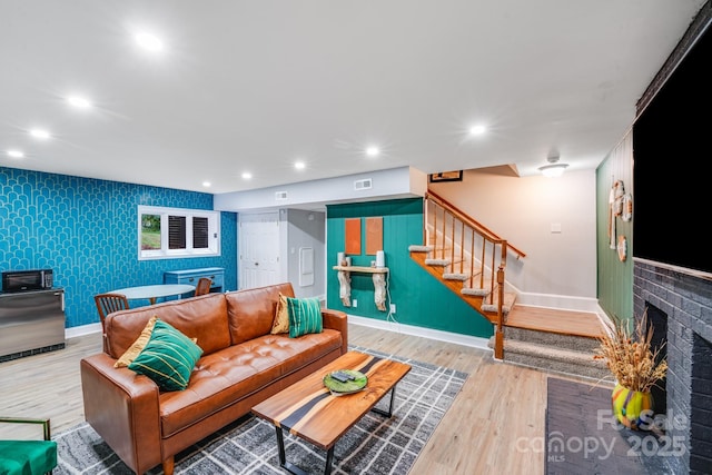 3920 Tilley Morris Rd, Matthews, NC 28105 - living area with an accent wall, stairs, wood finished floors, a brick fireplace, and recessed lighting