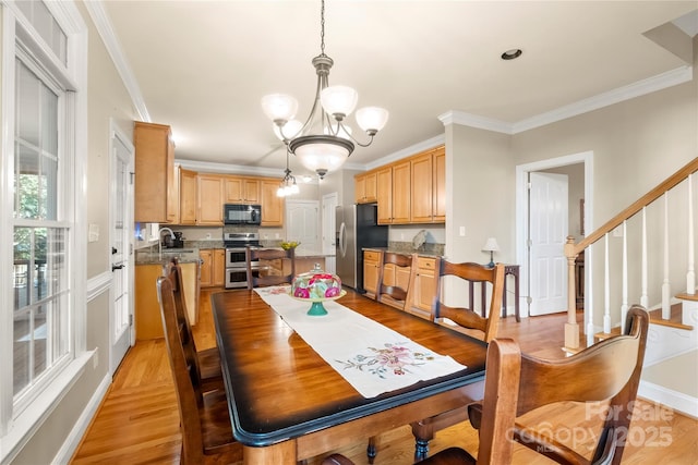6123 Abergele Ln, Matthews, NC 28104 - dining space featuring a chandelier, light wood-style flooring, crown molding, and stairs