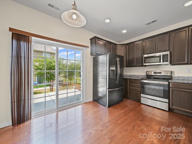 15239 Wrights Crossing Dr, Charlotte, NC 28278 - kitchen featuring stainless steel appliances, dark brown cabinetry, light stone counters, dark wood-type flooring, and recessed lighting