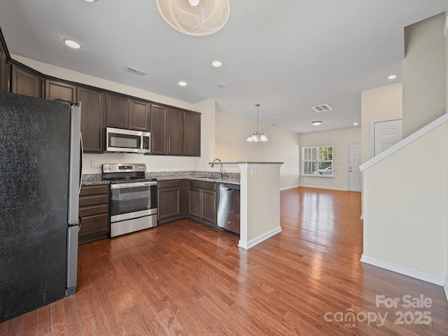 15239 Wrights Crossing Dr, Charlotte, NC 28278 - kitchen with stainless steel appliances, a peninsula, dark brown cabinetry, dark wood-style floors, and a chandelier