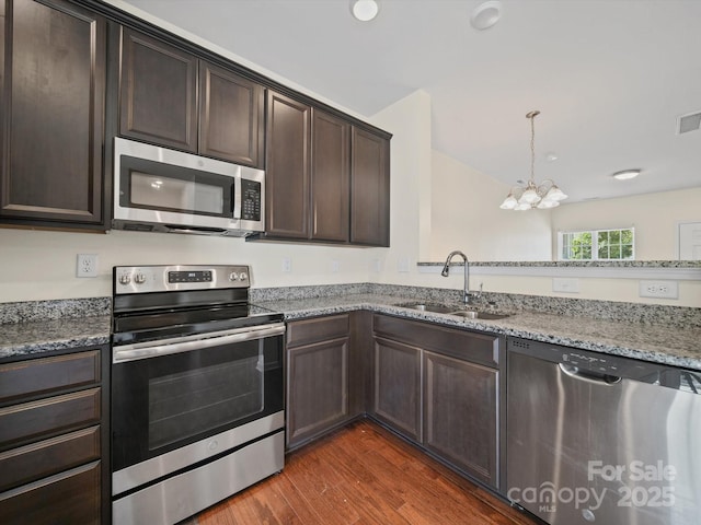 15239 Wrights Crossing Dr, Charlotte, NC 28278 - kitchen featuring appliances with stainless steel finishes, a chandelier, dark brown cabinetry, dark wood finished floors, and light stone counters