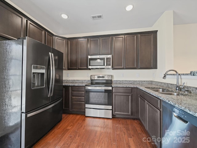 15239 Wrights Crossing Dr, Charlotte, NC 28278 - kitchen featuring appliances with stainless steel finishes, dark brown cabinetry, light stone counters, dark wood-style floors, and recessed lighting