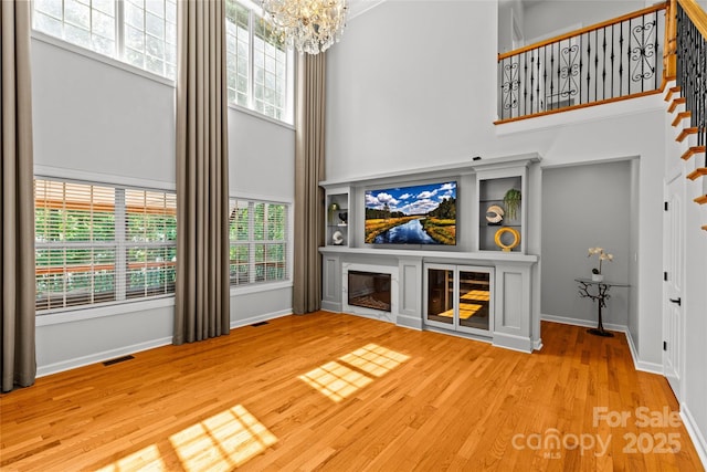 12336 Tantallon Ct, Pineville, NC 28134 - unfurnished living room with a towering ceiling, a chandelier, healthy amount of natural light, wood finished floors, and stairs