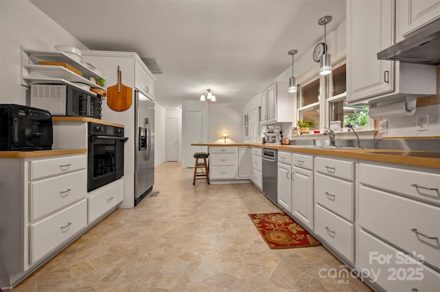 467 Winners Cir, Tryon, NC 28782 - kitchen featuring stainless steel appliances, under cabinet range hood, a peninsula, white cabinets, and light stone finish floors