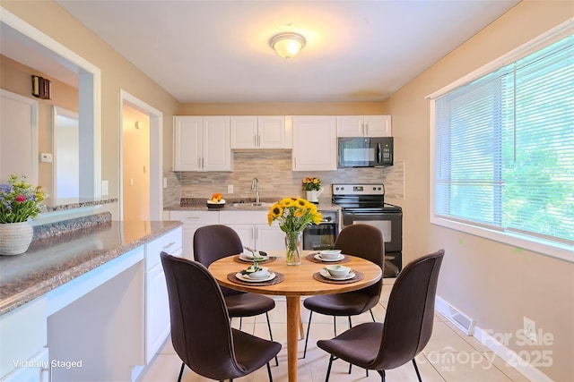2519 Abelwood Rd, Charlotte, NC 28216 - kitchen with electric range oven, black microwave, decorative backsplash, and white cabinets