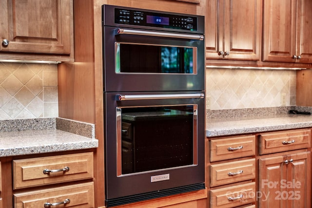 8448 Normandy Rd, Denver, NC 28037 - kitchen featuring multiple ovens, backsplash, brown cabinetry, and light stone counters