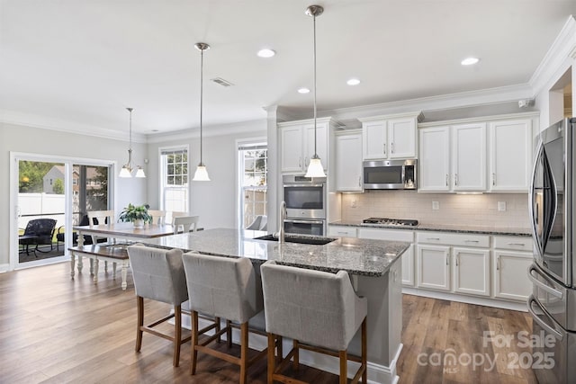 10906 Angler Ct, Davidson, NC 28036 - kitchen featuring stainless steel appliances, white cabinetry, ornamental molding, tasteful backsplash, and wood finished floors