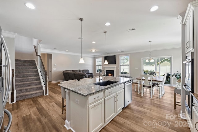 10906 Angler Ct, Davidson, NC 28036 - kitchen featuring stainless steel appliances, a warm lit fireplace, crown molding, open floor plan, and light wood-style floors