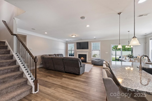 10906 Angler Ct, Davidson, NC 28036 - living room featuring ornamental molding, stairway, wood finished floors, recessed lighting, and a lit fireplace