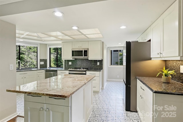 9334 Hunting Ct, Matthews, NC 28105 - kitchen with stainless steel appliances, decorative backsplash, white cabinets, dark stone countertops, and recessed lighting