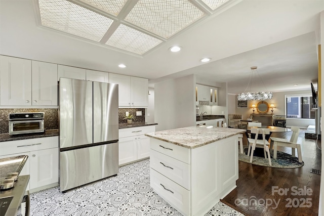 9334 Hunting Ct, Matthews, NC 28105 - kitchen featuring freestanding refrigerator, recessed lighting, tasteful backsplash, white cabinetry, and light stone counters
