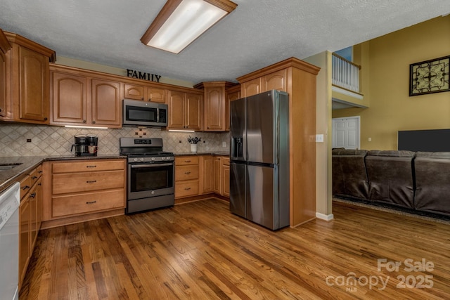59 Old Lakey Gap Rd, Black Mountain, NC 28711 - kitchen featuring stainless steel appliances, dark wood finished floors, decorative backsplash, open floor plan, and a textured ceiling