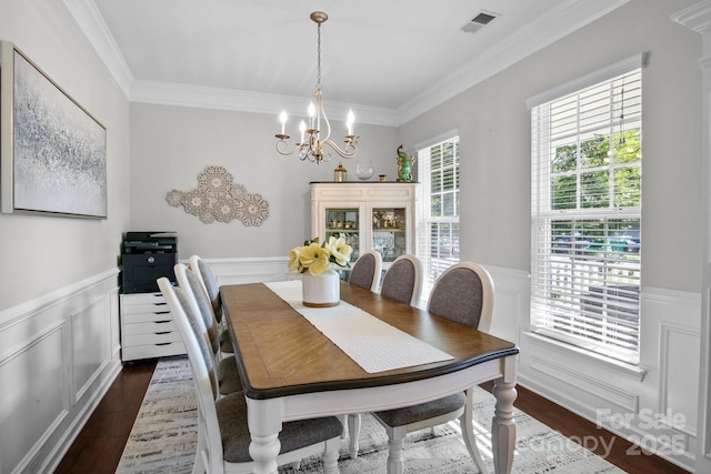 10621 Shanon Darby Ln, Charlotte, NC 28214 - dining space featuring a chandelier, a wainscoted wall, crown molding, dark wood-style flooring, and a decorative wall