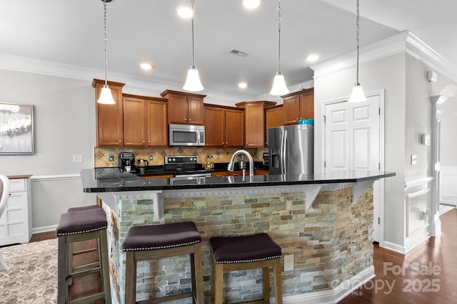 10621 Shanon Darby Ln, Charlotte, NC 28214 - kitchen featuring stainless steel appliances, ornamental molding, dark wood-style floors, backsplash, and brown cabinets