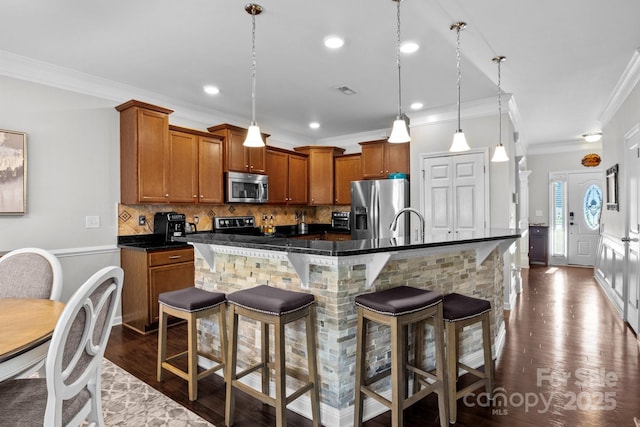 10621 Shanon Darby Ln, Charlotte, NC 28214 - kitchen featuring appliances with stainless steel finishes, crown molding, brown cabinetry, a breakfast bar, and dark wood-style flooring