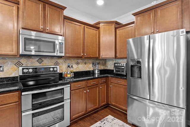 10621 Shanon Darby Ln, Charlotte, NC 28214 - kitchen with appliances with stainless steel finishes, dark wood finished floors, brown cabinets, dark stone countertops, and recessed lighting