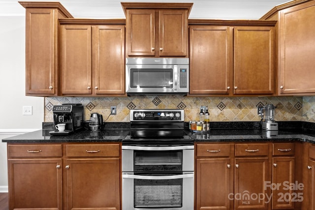 10621 Shanon Darby Ln, Charlotte, NC 28214 - kitchen featuring stainless steel appliances, decorative backsplash, brown cabinetry, and dark stone counters