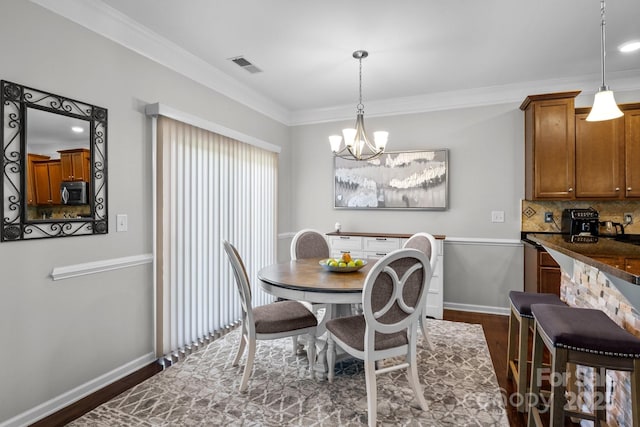 10621 Shanon Darby Ln, Charlotte, NC 28214 - dining area featuring a chandelier, dark wood-style flooring, and crown molding