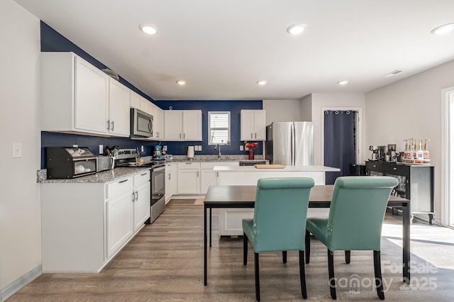 1478 Cannan Mountain Dr, Newton, NC 28658 - kitchen with stainless steel appliances, white cabinetry, light wood-style floors, a center island, and recessed lighting