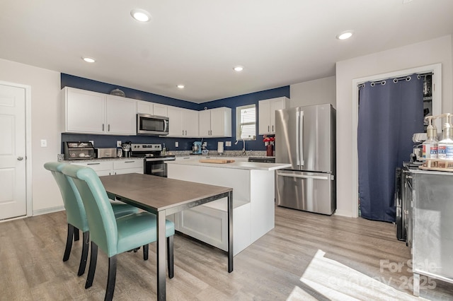 1478 Cannan Mountain Dr, Newton, NC 28658 - kitchen with appliances with stainless steel finishes, white cabinetry, light wood-type flooring, a center island, and recessed lighting