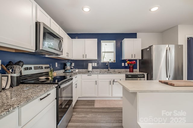 1478 Cannan Mountain Dr, Newton, NC 28658 - kitchen with appliances with stainless steel finishes, wood finished floors, white cabinetry, recessed lighting, and light stone countertops