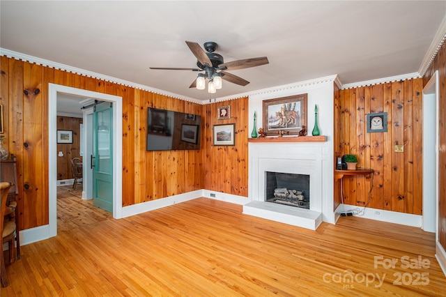 806 S Point Rd, Belmont, NC 28012 - unfurnished living room featuring ornamental molding, ceiling fan, a fireplace with raised hearth, light wood finished floors, and wood walls