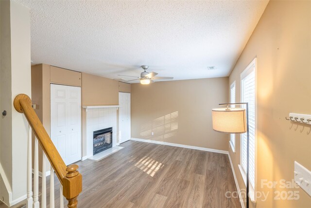 1533 20th Ave NE, Hickory, NC 28601 - unfurnished living room with wood finished floors, a ceiling fan, a textured ceiling, and a fireplace