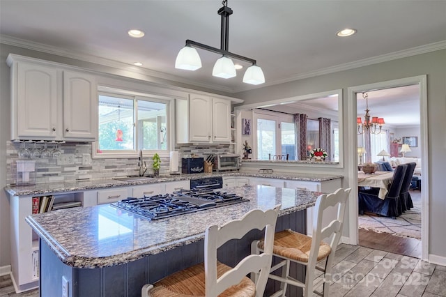 17 Heritage Dr, Lake Wylie, SC 29710 - kitchen featuring gas cooktop, a kitchen island, a breakfast bar, plenty of natural light, and ornamental molding