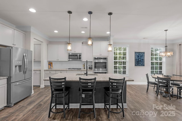 236 Robinwood Ln, Clover, SC 29710 - kitchen featuring appliances with stainless steel finishes, crown molding, decorative backsplash, dark wood-type flooring, and a kitchen island with sink