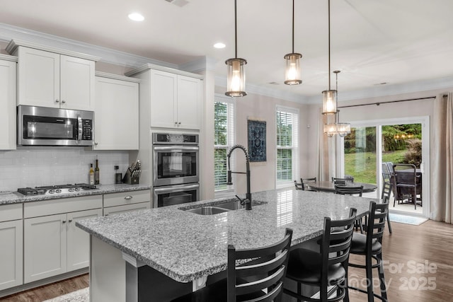 236 Robinwood Ln, Clover, SC 29710 - kitchen featuring appliances with stainless steel finishes, ornamental molding, an island with sink, decorative backsplash, and a kitchen breakfast bar