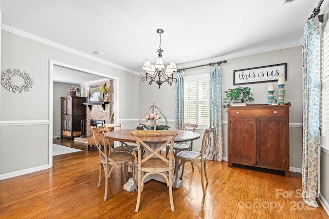 2838 Candleberry Ct, Charlotte, NC 28210 - dining space featuring a chandelier, ornamental molding, light wood-style floors, and a fireplace