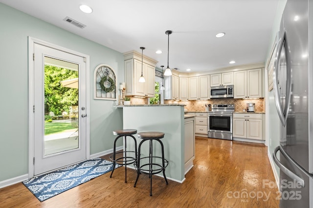 2838 Candleberry Ct, Charlotte, NC 28210 - kitchen featuring stainless steel appliances, a peninsula, wood finished floors, a breakfast bar, and backsplash