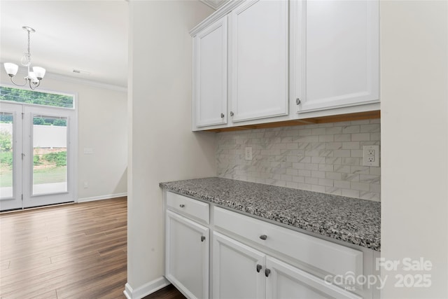 15213 Red Canoe Way, Charlotte, NC 28278 - kitchen featuring a chandelier, decorative backsplash, white cabinetry, dark wood-style flooring, and light stone countertops