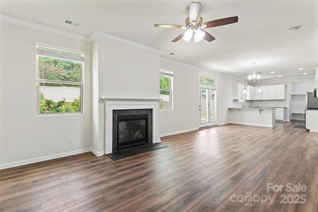 15213 Red Canoe Way, Charlotte, NC 28278 - unfurnished living room with dark wood finished floors, ornamental molding, a chandelier, a glass covered fireplace, and ceiling fan