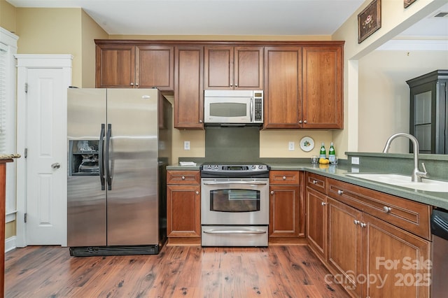 13714 Morehouse St, Huntersville, NC 28078 - kitchen featuring appliances with stainless steel finishes, dark wood-style flooring, brown cabinets, and dark countertops